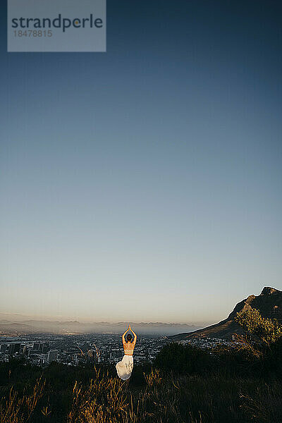 Frau praktiziert Yoga auf dem Signal Hill bei Sonnenuntergang