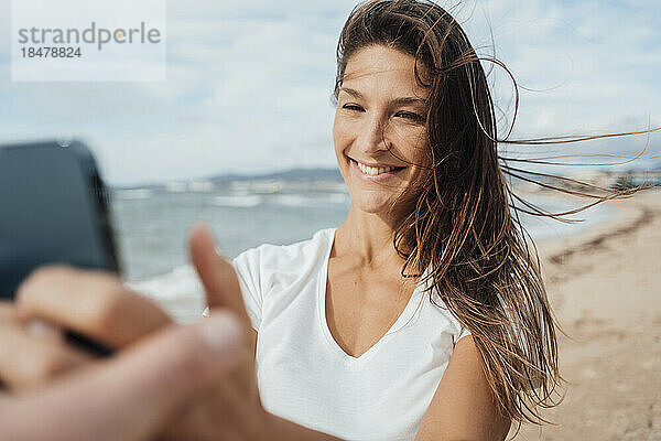 Glückliche Frau  die am Strand ein Selfie mit dem Handy macht