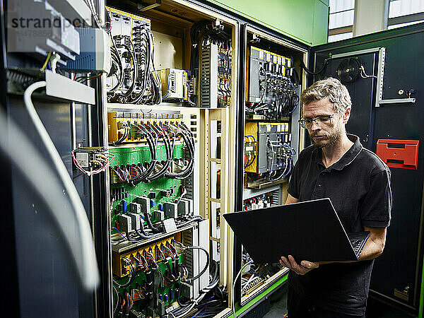 Techniker benutzt Laptop an der Maschine in einer modernen Fabrik