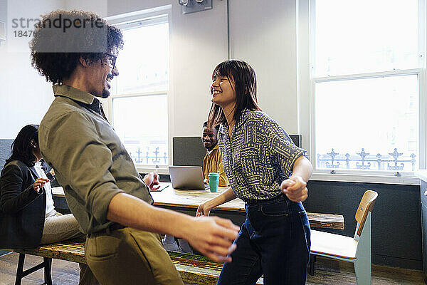 Geschäftsfrau tanzt mit Kollegin am Arbeitsplatz