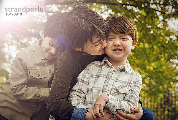 Junge küsst Bruder an sonnigem Tag im Park