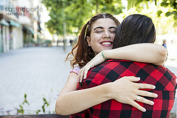 Glückliches lesbisches Paar  das sich auf dem Fußweg umarmt