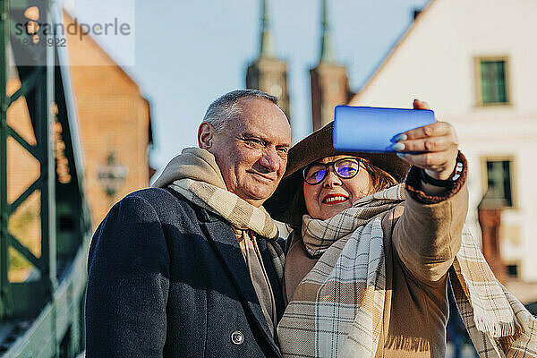 Lächelnde ältere Frau macht Selfie mit Mann über Mobiltelefon