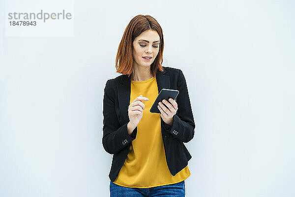Geschäftsfrau benutzt Smartphone vor weißem Hintergrund