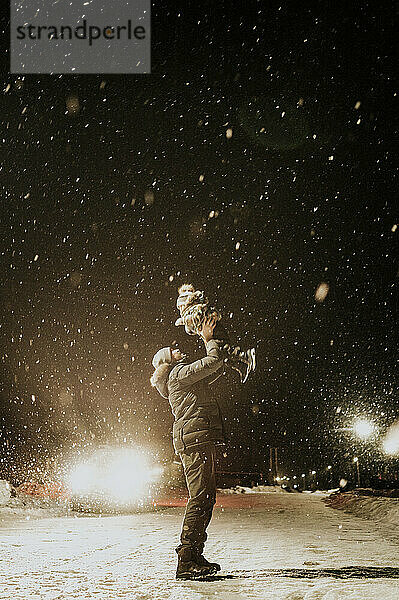 Vater und Sohn amüsieren sich im Schnee auf der Straße