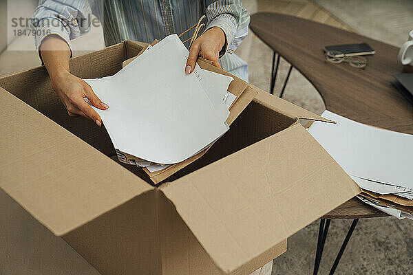 Hände einer Frau  die zu Hause Papiere in einer Schachtel recycelt