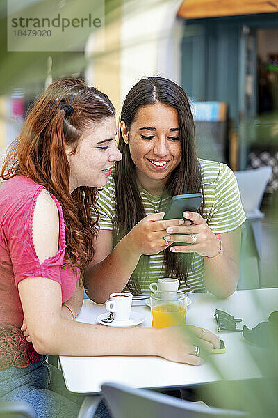 Frau teilt Smartphone mit Freundin im Straßencafé