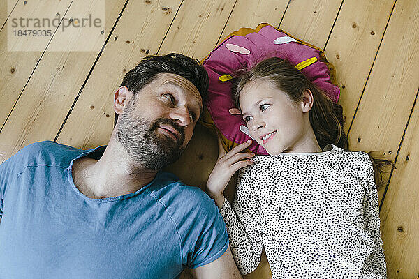Father looking at daughter lying on floor in home