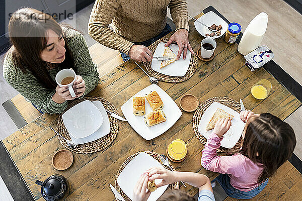 Mann und Frau frühstücken mit Kindern am Tisch
