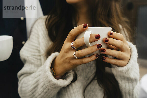 Hände einer Frau mit Kaffeetasse im Kuppelzelt