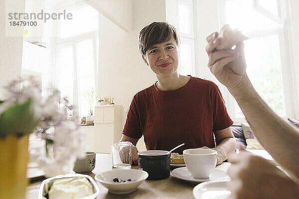 Lächelnde Frau mit Frühstück auf dem heimischen Tisch
