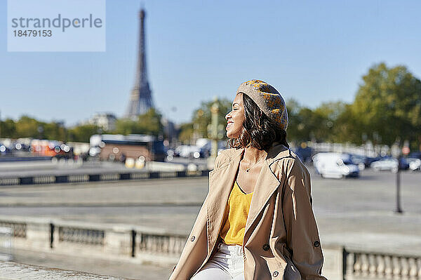 Junge Frau trägt Baskenmütze am Fußweg an einem sonnigen Tag