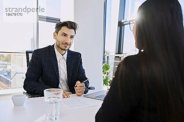 Recruiter with document talking to candidate in interview at office