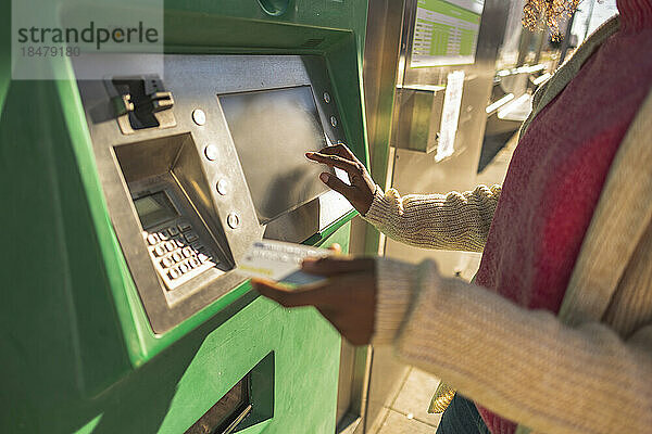 Junge Frau mit Kreditkarte am Geldautomaten