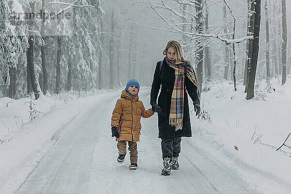 Mutter geht mit Sohn im verschneiten Wald unterwegs