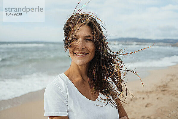 Glückliche Frau mit langen Haaren verbringt ihre Freizeit am Strand