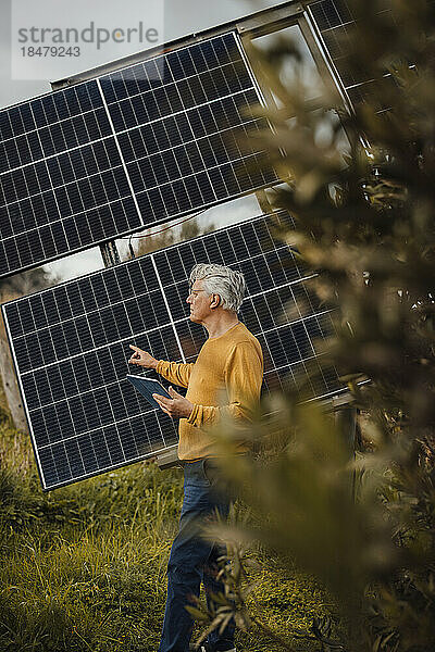 Älterer Mann mit Tablet-PC untersucht Sonnenkollektoren