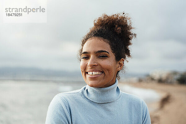 Glückliche junge Frau mit Afro-Frisur am Strand
