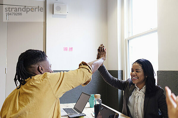 Geschäftsfrau gibt einem Kollegen am Arbeitsplatz High-Five