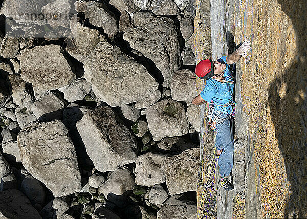 Sportler klettert an sonnigem Tag auf Felswand