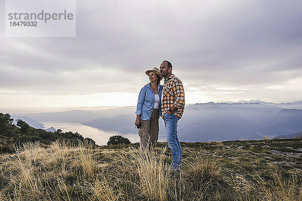 Älteres Paar steht bei Sonnenuntergang zusammen auf dem Berg