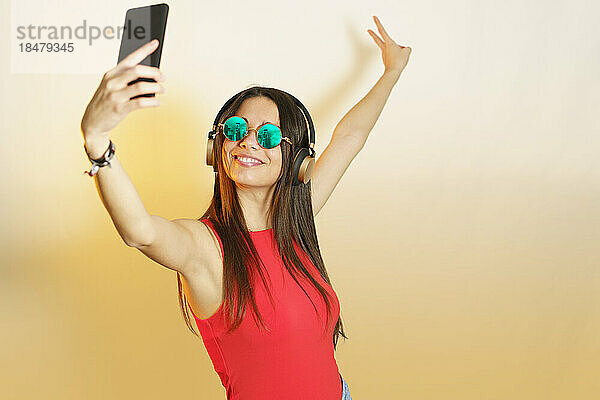 Lächelnde Frau mit Steampunk-Brille  die ein Selfie mit dem Smartphone macht