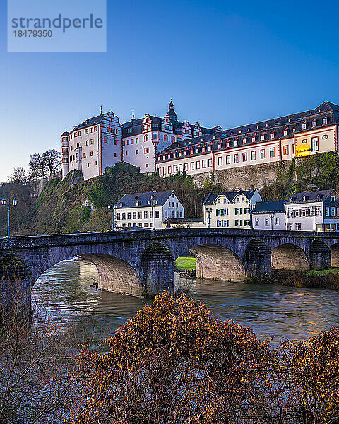 Schloss Weilburg mit Fluss und alter Lahnbrücke unter blauem Himmel