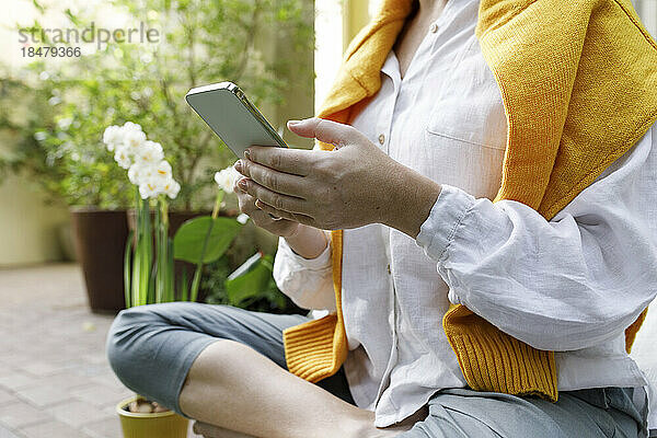 Frau schreibt Textnachrichten per Smartphone im Hinterhof