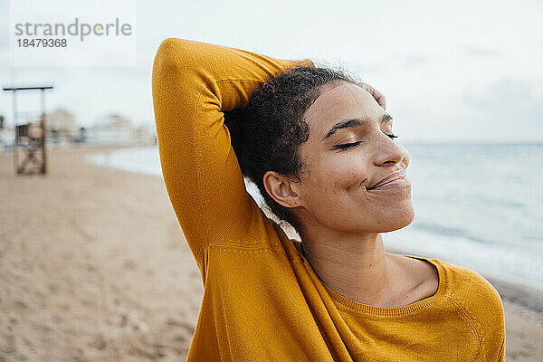 Smiling young woman with eyes closed at beach