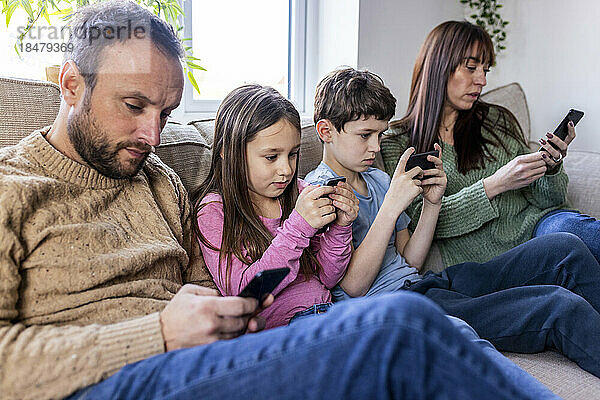 Familie benutzt Smartphone auf Sofa zu Hause