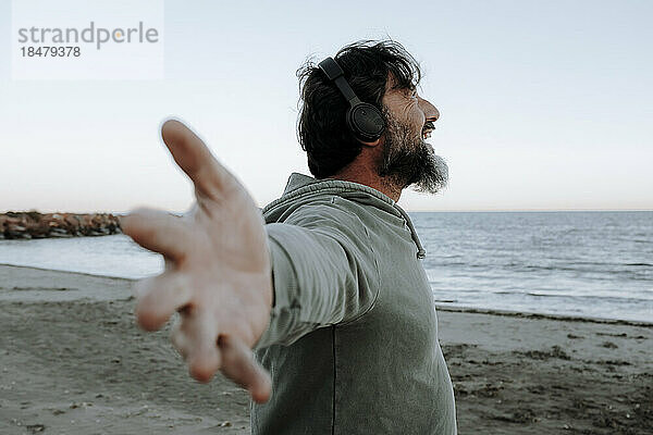 Happy man with arms outstretched enjoying at beach