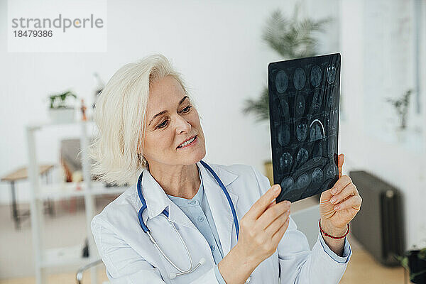 Lächelnder Arzt untersucht medizinisches Röntgen in der Klinik