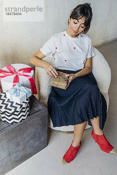 Lächelnde Frau mit Geschenkboxen  die auf einem Stuhl sitzt