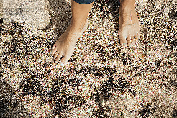 Frau steht barfuß im Sand am Strand