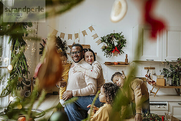 Fröhliche Familie umarmt sich und genießt Weihnachten in der Küche