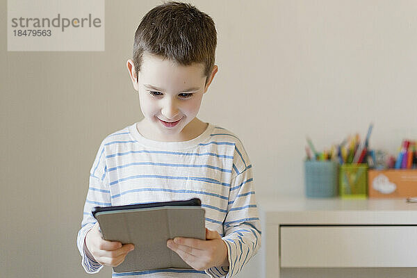 Lächelnder Junge schaut sich zu Hause einen Tablet-PC an