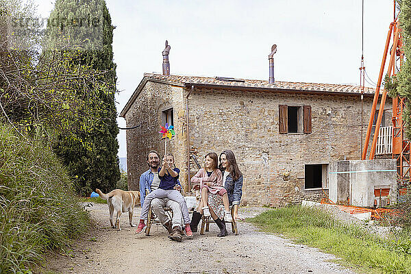 Glückliche Familie mit Hund  der vor dem Haus sitzt