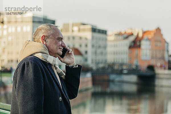 Älterer Mann in warmer Kleidung  der mit dem Handy telefoniert