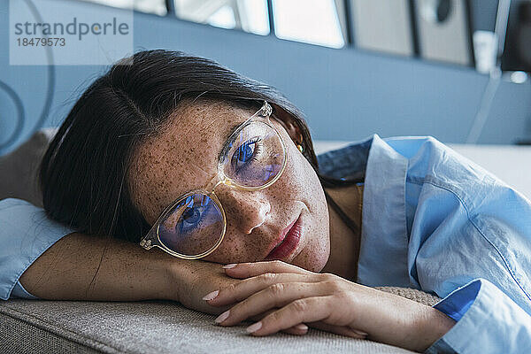 Young woman with eyeglasses resting on sofa at home