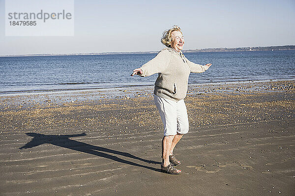 Glückliche ältere Frau  die an einem sonnigen Tag vor dem Meer genießt