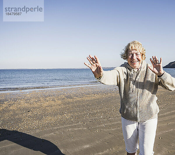Fröhliche ältere Frau am Strand an einem sonnigen Tag