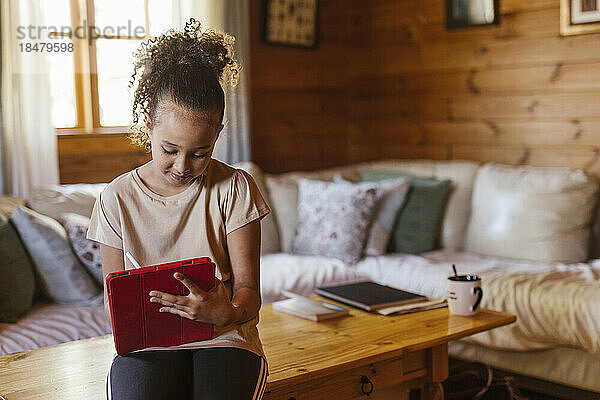 Mädchen benutzt Tablet-PC und sitzt zu Hause am Tisch