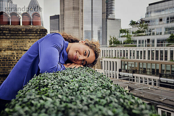 Lächelnde Geschäftsfrau  die sich auf Pflanzen ausruht