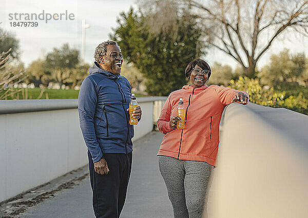 Glückliches Paar mit Energy-Drinks  das Spaß am Geländer hat