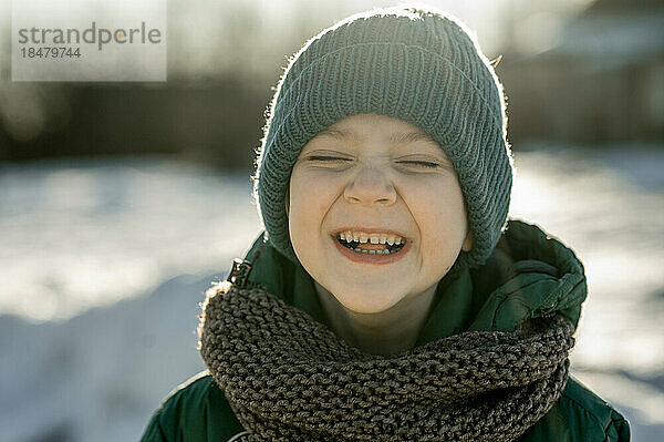 Fröhlicher Junge mit Strickmütze im Winter