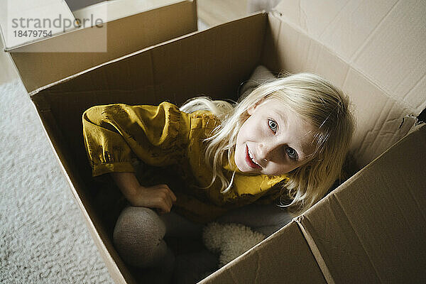 Girl sitting inside cardboard box at home