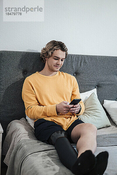 Mann benutzt Smartphone zu Hause im Bett