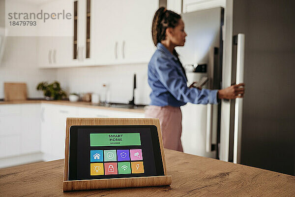 Hausautomations-App auf einem Tablet-Computer mit einer Frau im Hintergrund
