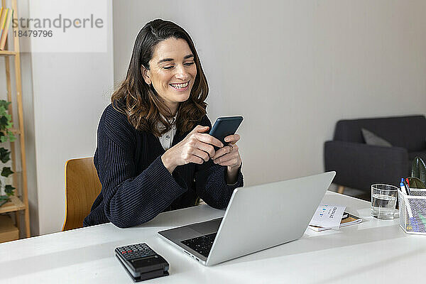 Glückliche Geschäftsfrau nutzt Smartphone im Büro