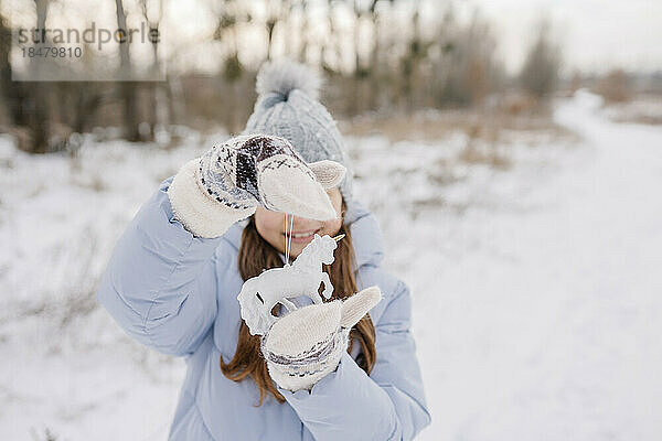 Lächelndes Mädchen mit Einhorn-Weihnachtsdekoration  das im Schnee steht